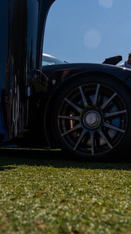 A close-up of a luxury car’s polished wheel and tire on a sunny day.