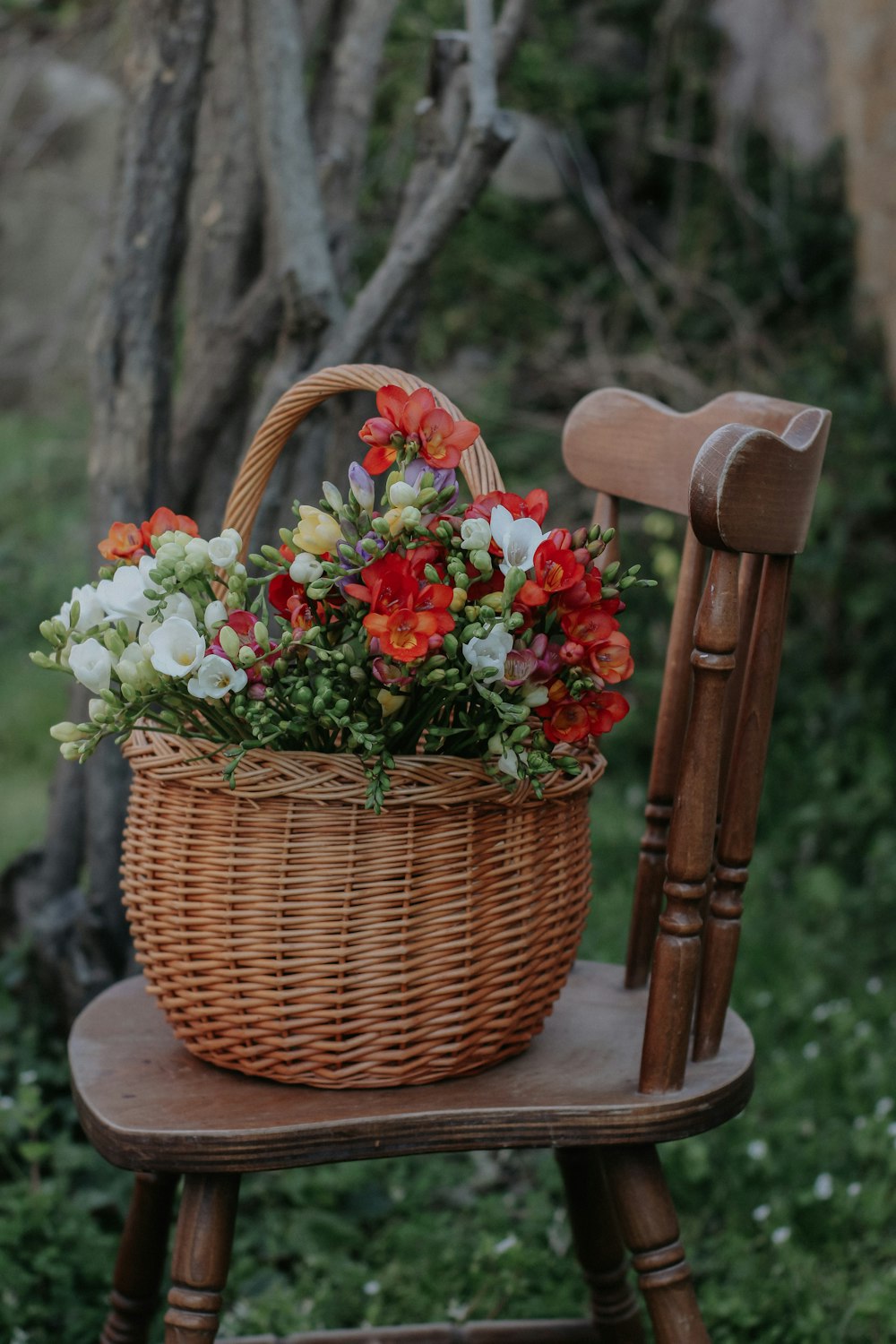 a basket of flowers sitting on top of a wooden chair
