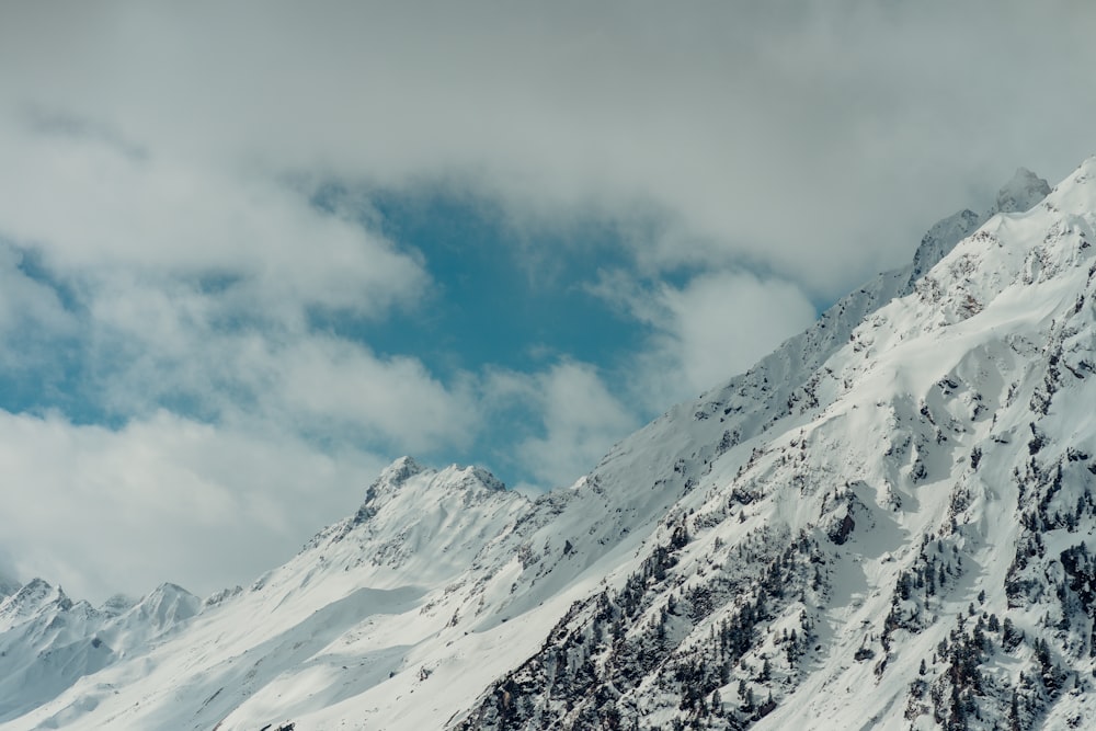 a mountain covered in snow under a cloudy sky