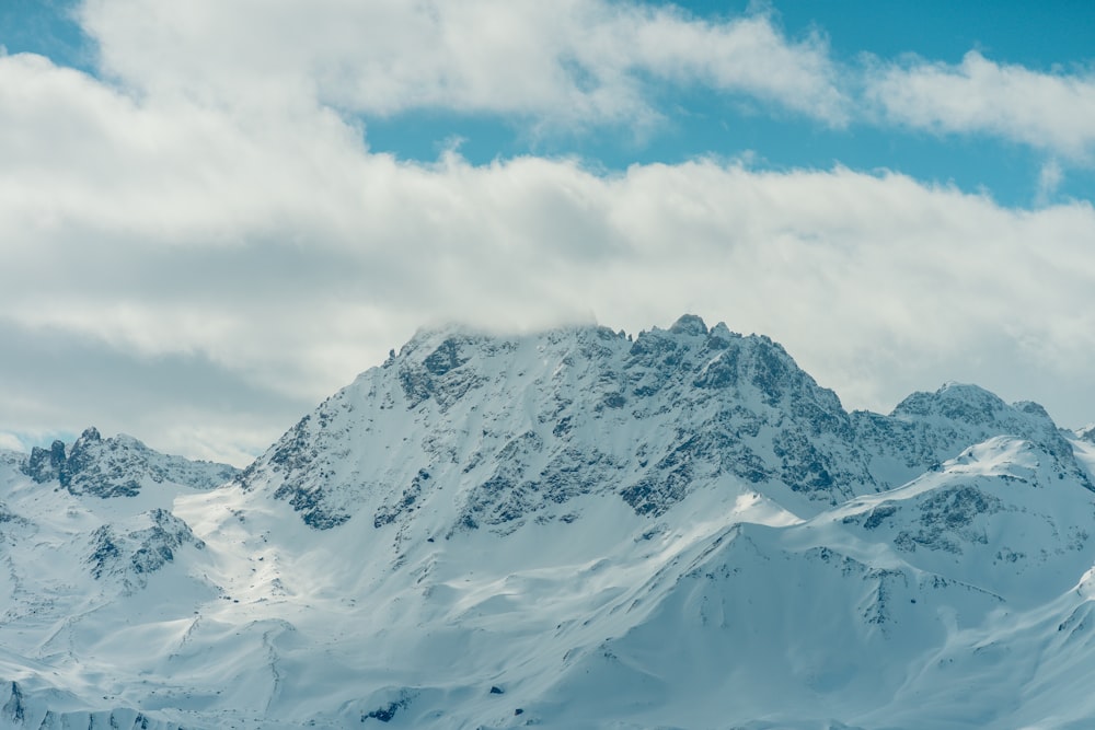 a mountain covered in snow under a cloudy blue sky