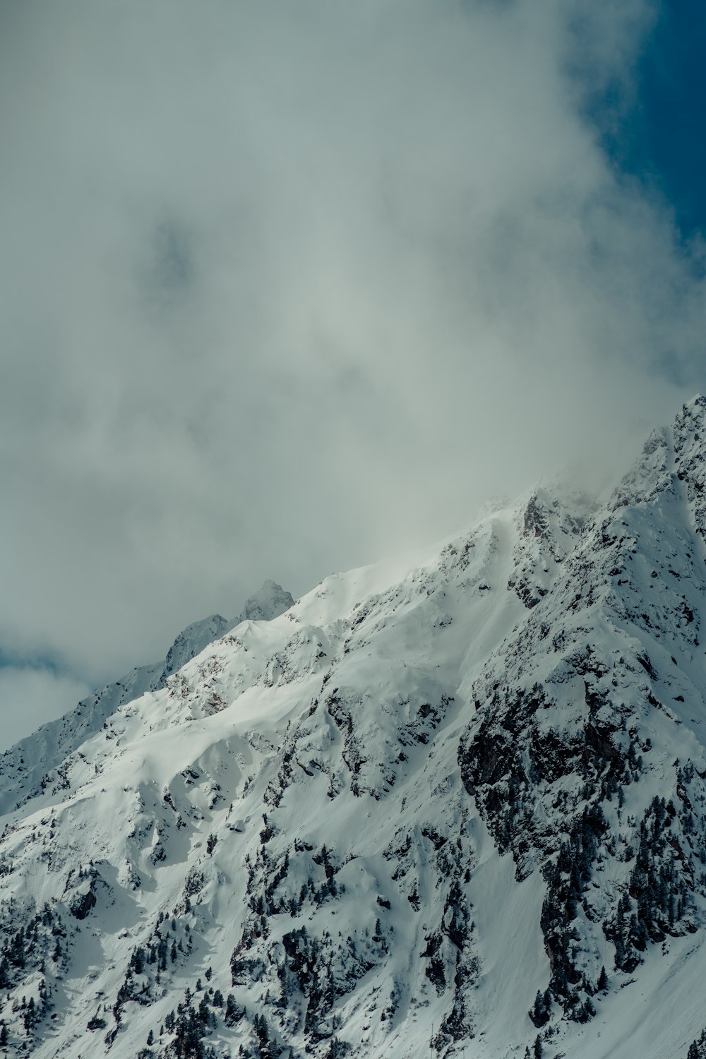 a mountain covered in snow under a cloudy sky