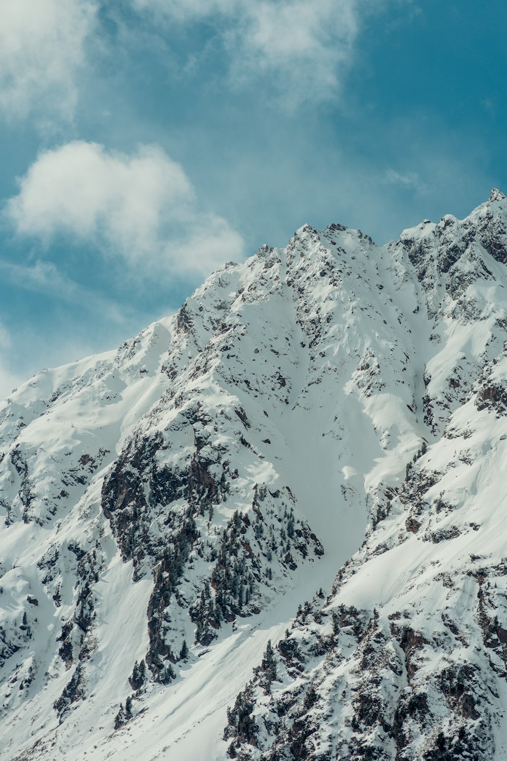 a snow covered mountain under a cloudy blue sky