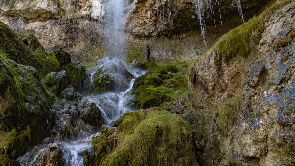 a man standing at the base of a waterfall