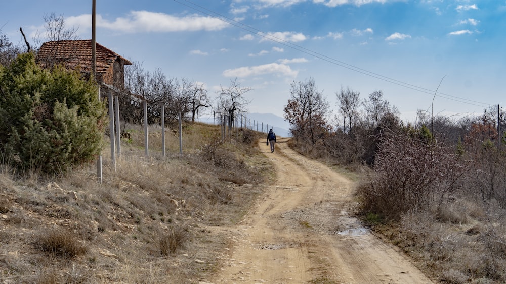 a dirt road with a person walking down it