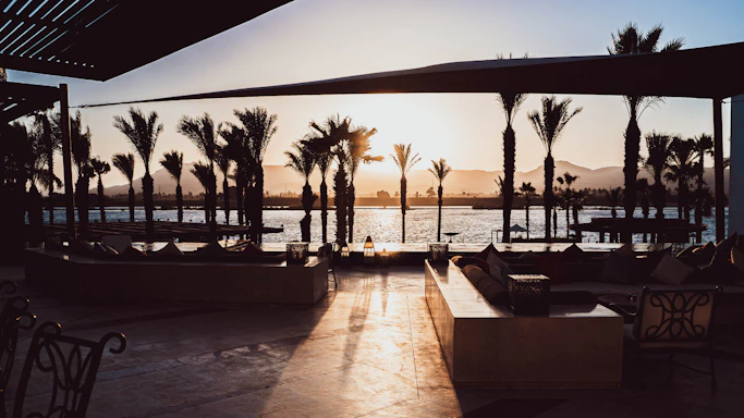 Warm sunset view of a cozy villa terrace with glowing lights and inviting seating.