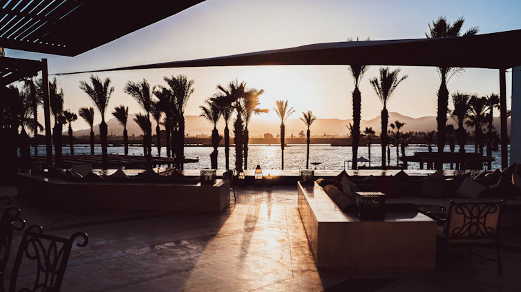 A warm sunset view over the lush garden area with guests enjoying a relaxed evening.