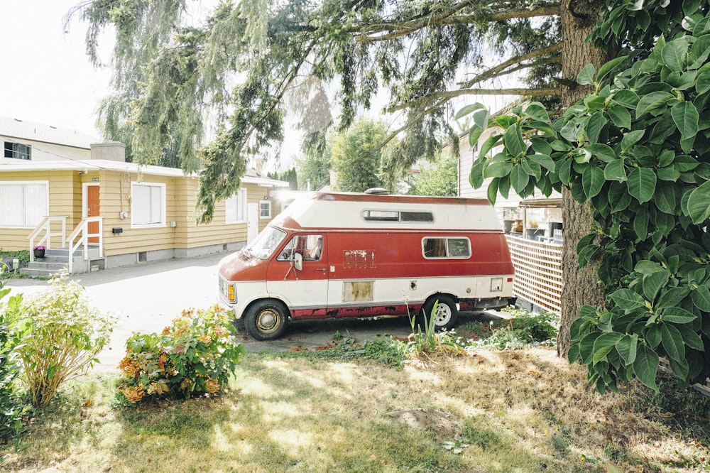 a red and white camper parked next to a tree
