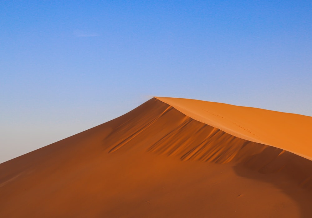 a large sand dune with a blue sky in the background