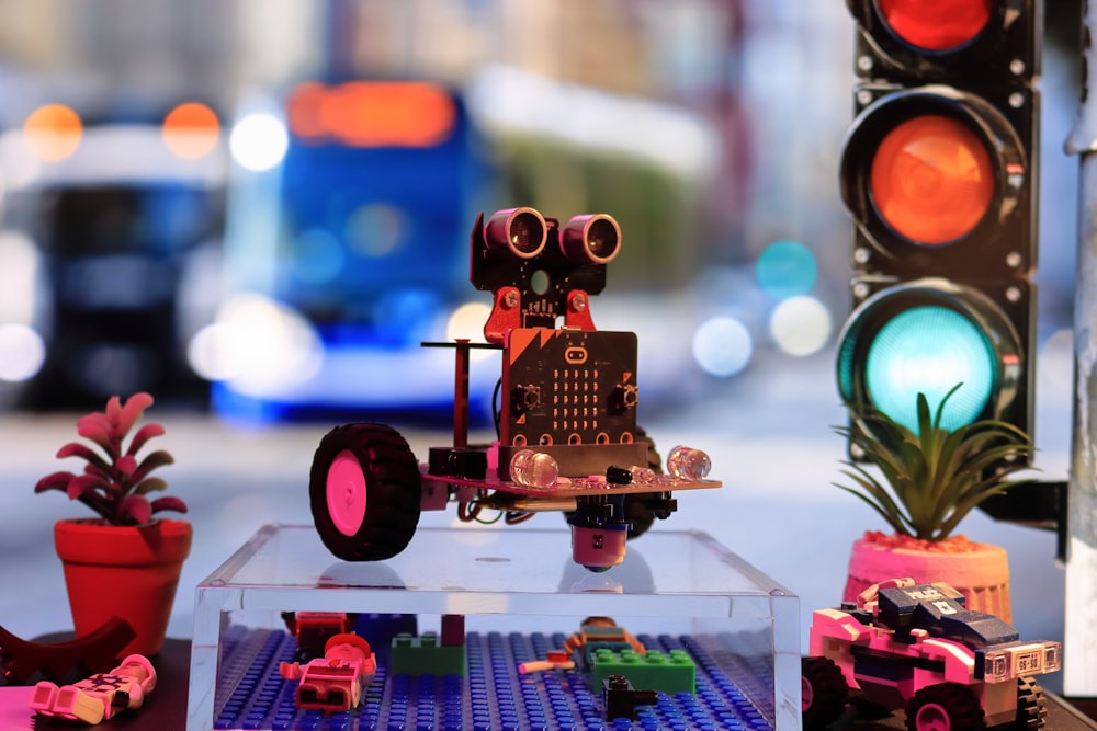 Un robot jouet est assis sur une table à côté d’un feu de circulation