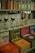 Various bottles of cleaning products are neatly organized on shelves, accompanied by colorful books with travel-themed covers. The upper shelf features sleek bottles with liquids in different hues, while the lower shelf displays vibrant books with titles such as 'Tulum', 'Bali', and 'Jaipur'. The arrangement suggests a boutique or specialty store layout.