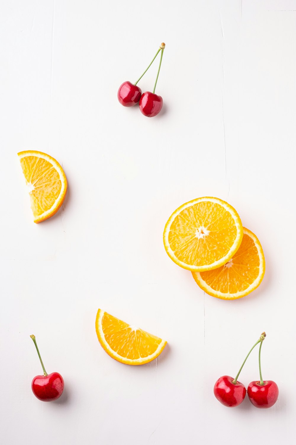 orange slices and cherries on a white surface