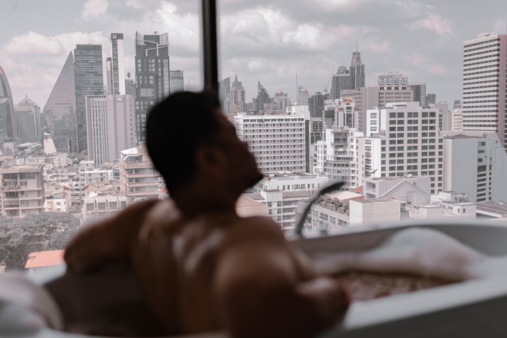 a man sitting in a bathtub looking out a window