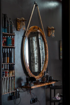a mirror hanging on a wall next to a shelf