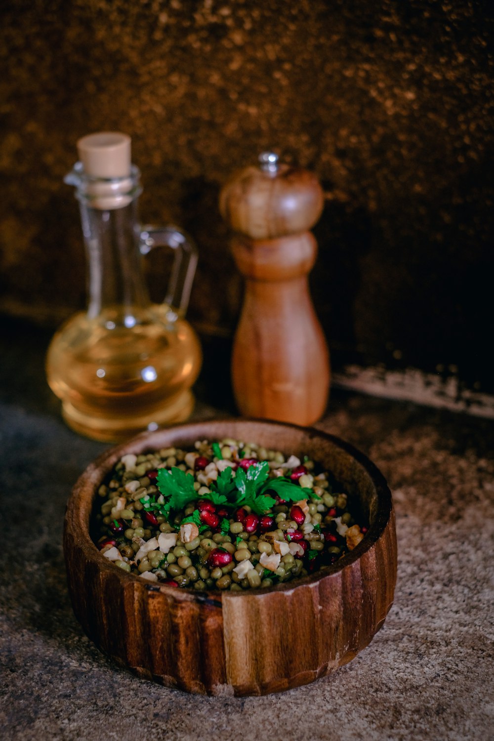 a wooden bowl filled with food next to a bottle of oil