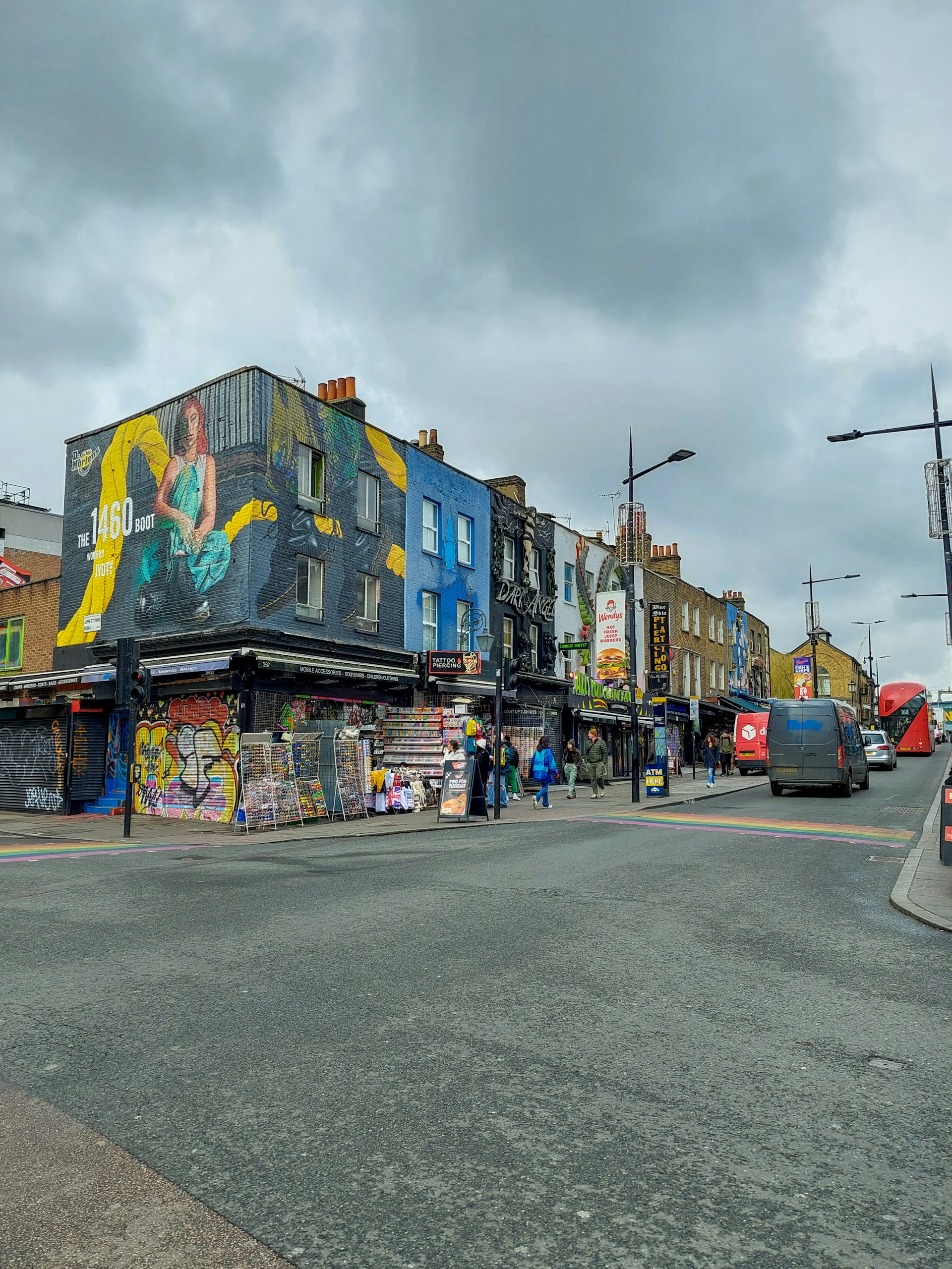 A colorful street scene showing the artist sketching a tattoo design outdoors during a sunny day.