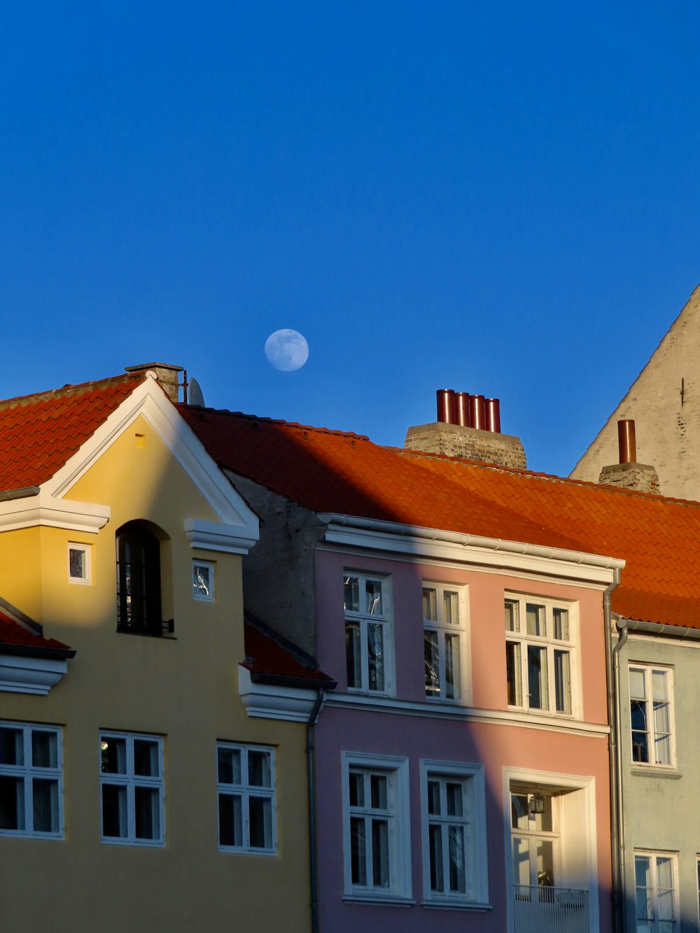 a row of buildings with a half moon in the background