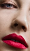 Close-up of a model with soft pink eyeshadow and bold red lips under natural light.