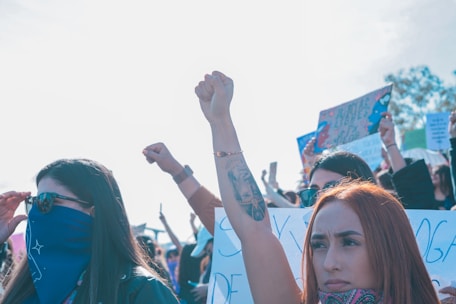 A diverse group of activists raising their elbows and fists together in solidarity at a Victoria protest.