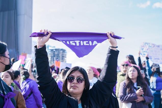 a woman holding up a purple scarf in front of a crowd