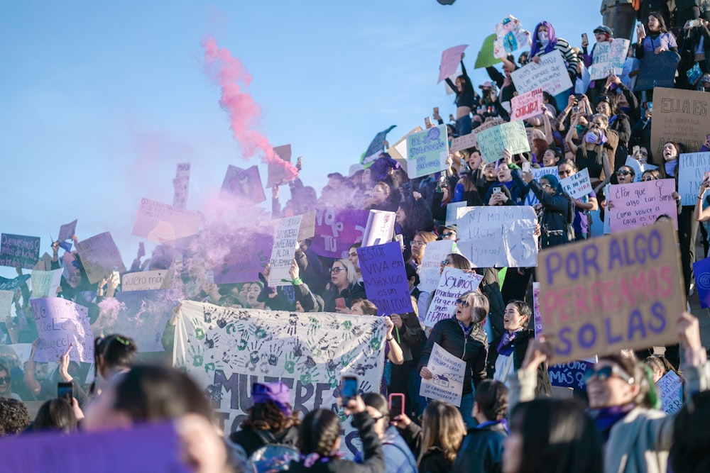 a crowd of people holding signs and smoke