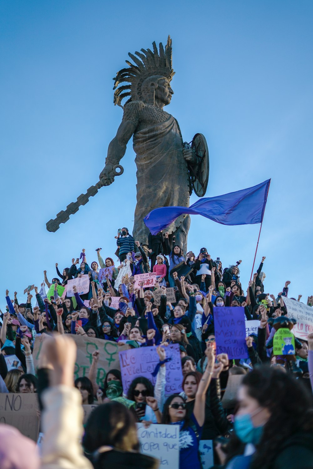 uma multidão de pessoas em pé em torno de uma estátua