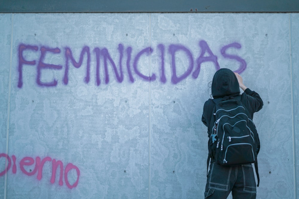 a person writing on a wall with graffiti
