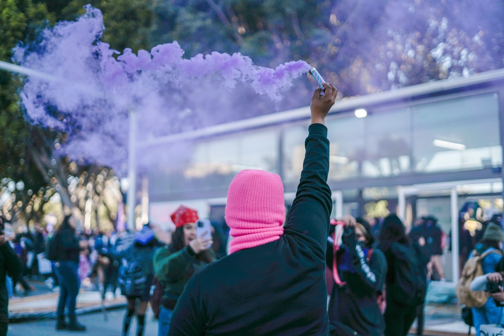 a person in a pink hat holding a purple smoke bomb