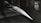 A model of a sleek, pointed aerospace vehicle with a sharp nose and aerodynamic fins is mounted inside a testing environment. The surroundings are metallic and industrial, with a perforated surface and visible instrumentation.