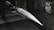 A model of a sleek, pointed aerospace vehicle with a sharp nose and aerodynamic fins is mounted inside a testing environment. The surroundings are metallic and industrial, with a perforated surface and visible instrumentation.