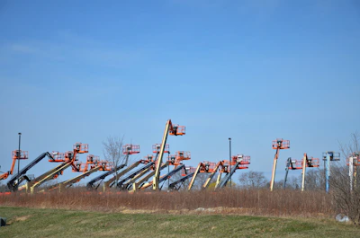 A row of clean, white and orange forklifts lined up outside the Powerlift store under a clear sky.