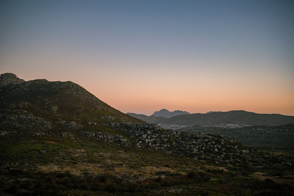 the sun is setting over the mountains in the distance