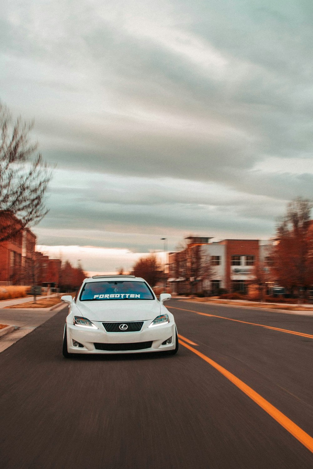 a white car driving down a street next to tall buildings