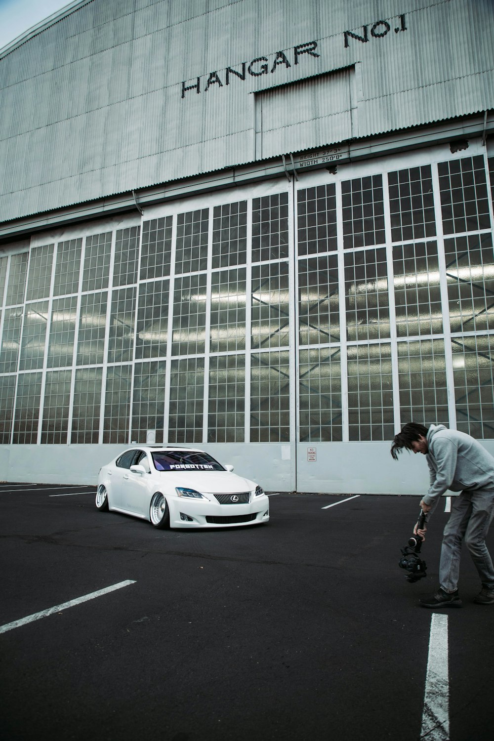 a man standing next to a white car in front of a building