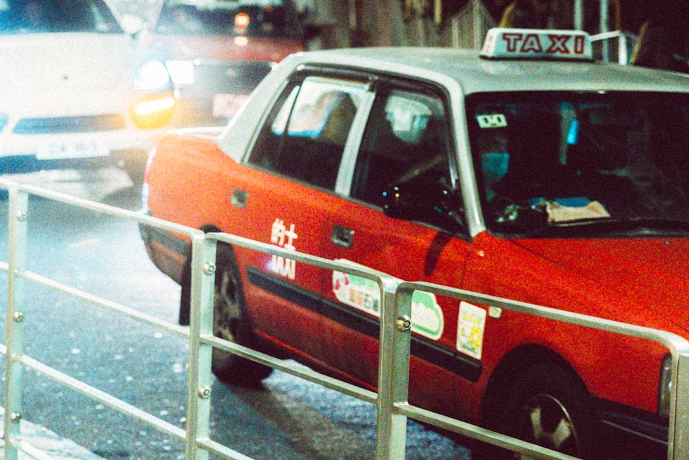 a red taxi cab driving down a street next to a traffic light