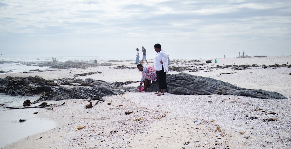 a group of people standing on top of a sandy beach