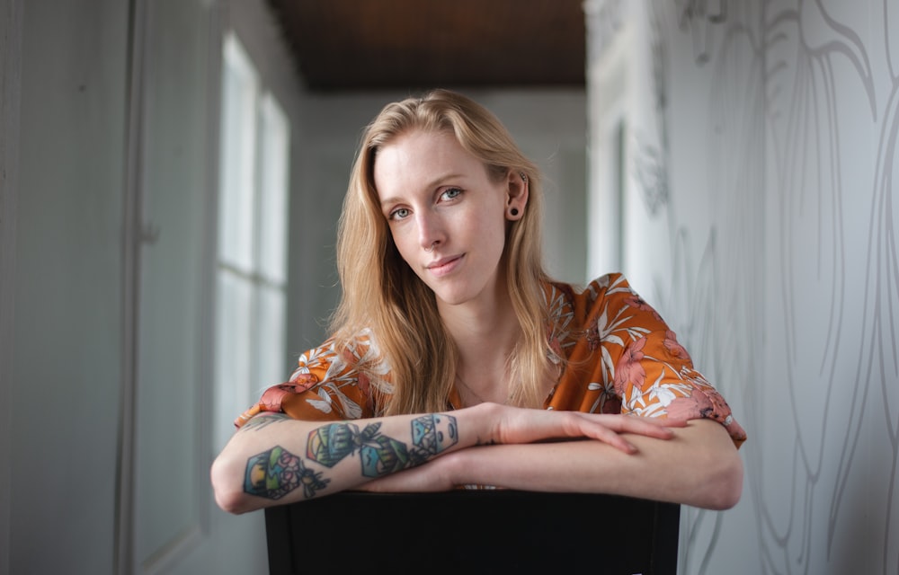 a woman with a tattoo on her arm sitting in a chair