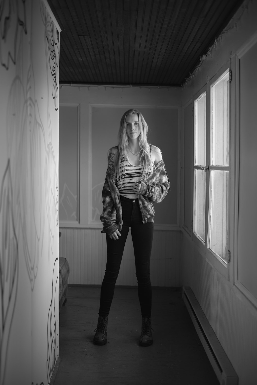 a black and white photo of a woman standing in a hallway