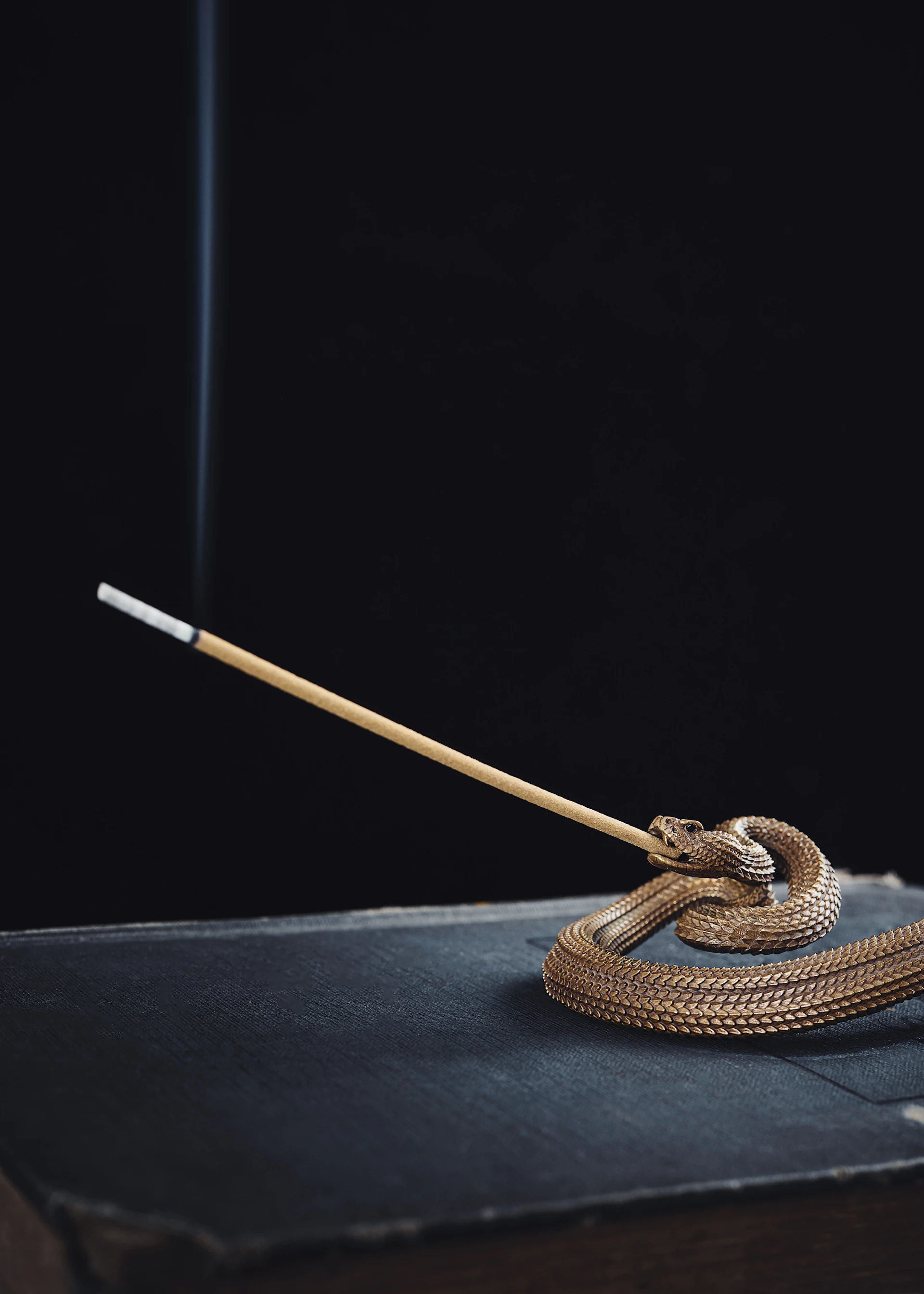 A peaceful corner featuring a golden incense holder with curling smoke, set against a minimalist white backdrop with subtle golden accents.