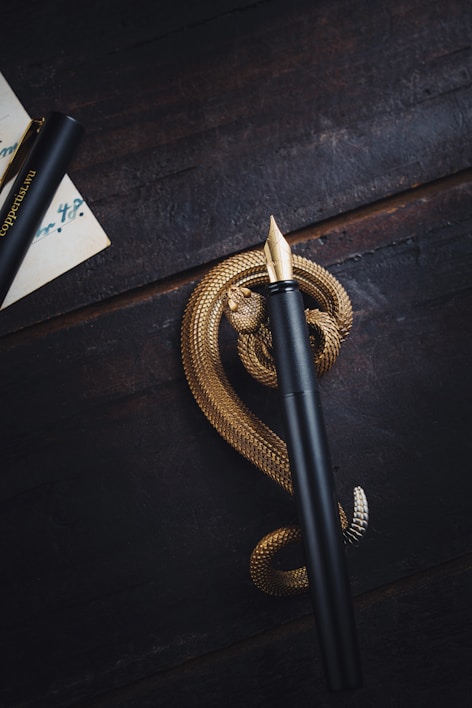 Close-up of a sleek black fountain pen resting on a wooden desk.