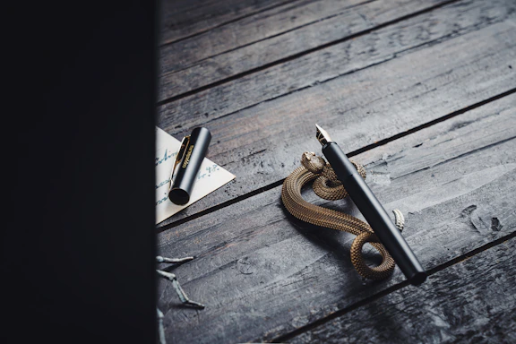 A sleek golden and silver pen resting on a dark surface beside a handwritten note.