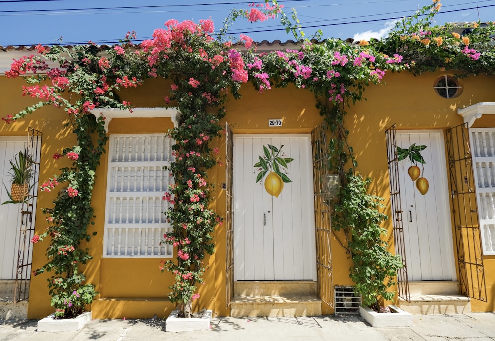 a yellow building with a bunch of flowers growing on it