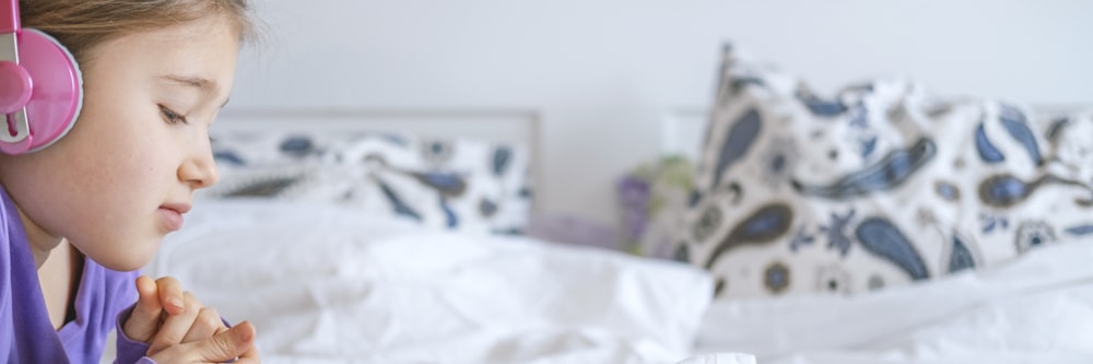 a little girl laying in bed with headphones on