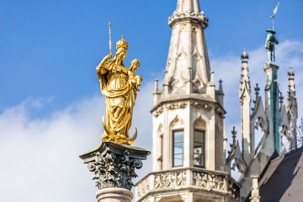 a golden statue on top of a pillar in front of a building