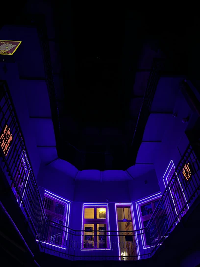 A sleek, futuristic workspace glowing with neon purple and electric blue lights, with a cosmic galaxy backdrop visible through a window.
