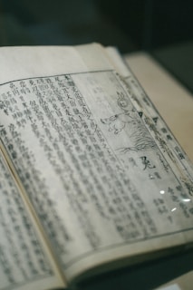 An open ancient Chinese medicine book with detailed illustrations of acupuncture points.