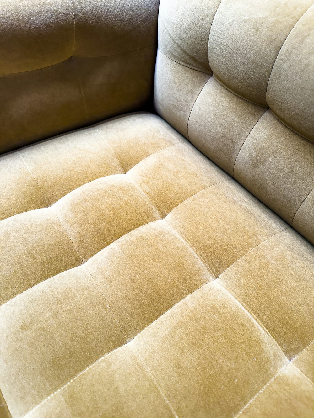 a close up of a tan couch with a brown pillow