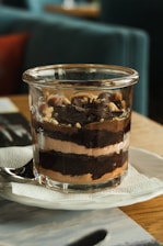 Close-up of a beautifully layered dessert jar with chocolate and cream, styled with rustic French elements.