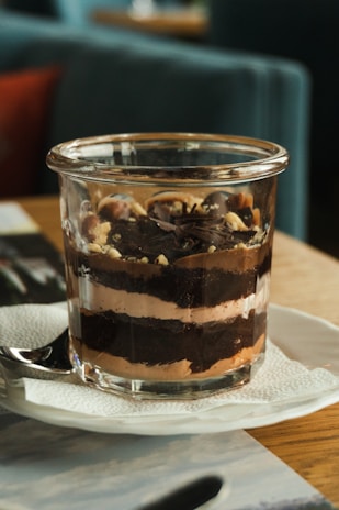 Close-up of a beautifully layered dessert jar with chocolate and cream, styled with rustic French elements.