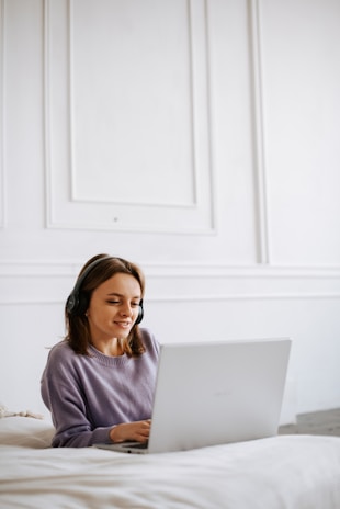 a woman sitting on a bed using a laptop computer