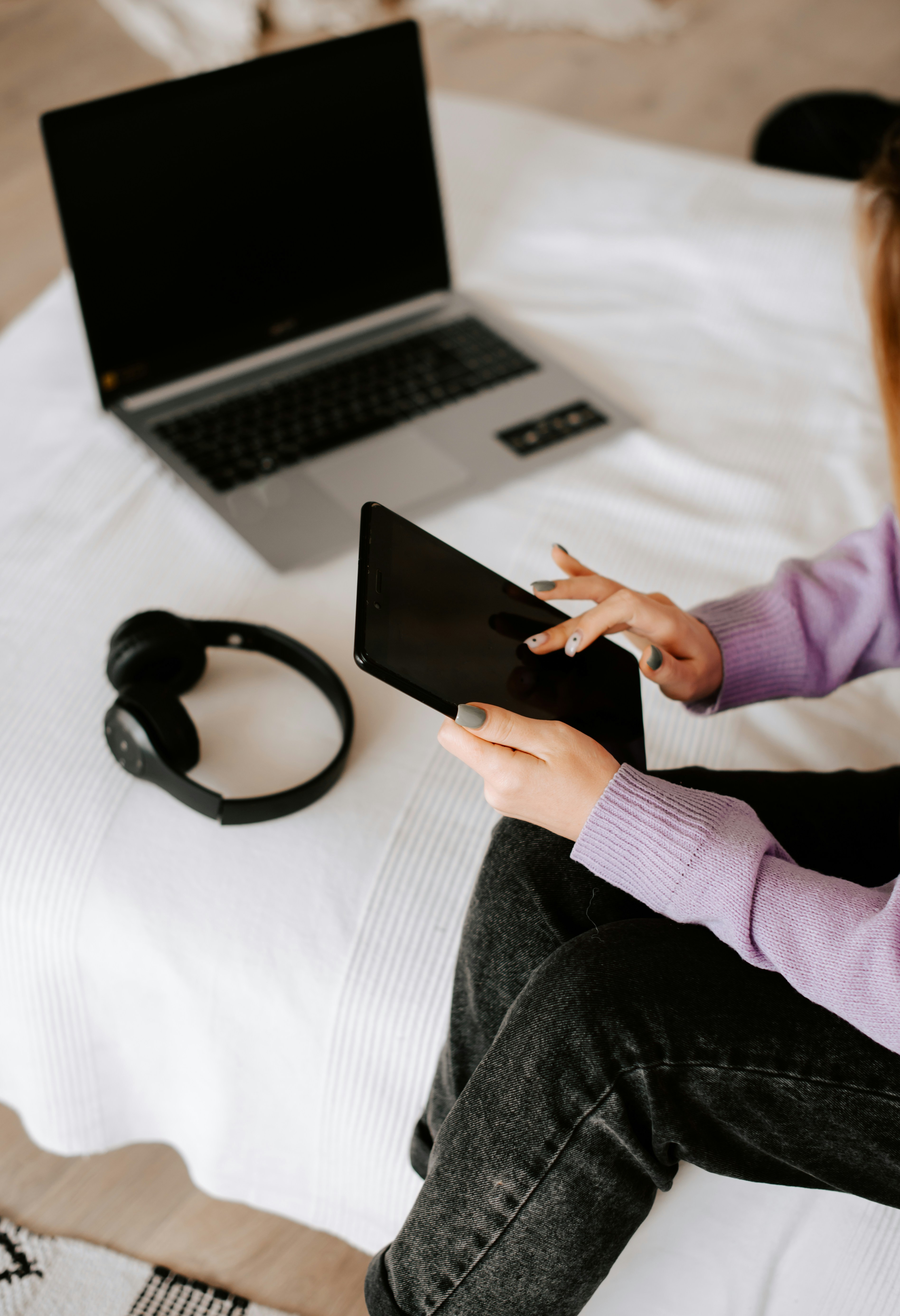 a woman sitting on a bed using a tablet